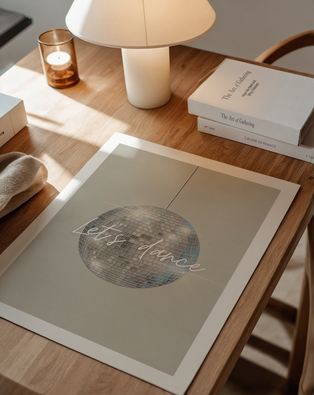 A neutral beige music print, laying on a table surrounded by decorative items and lamp.