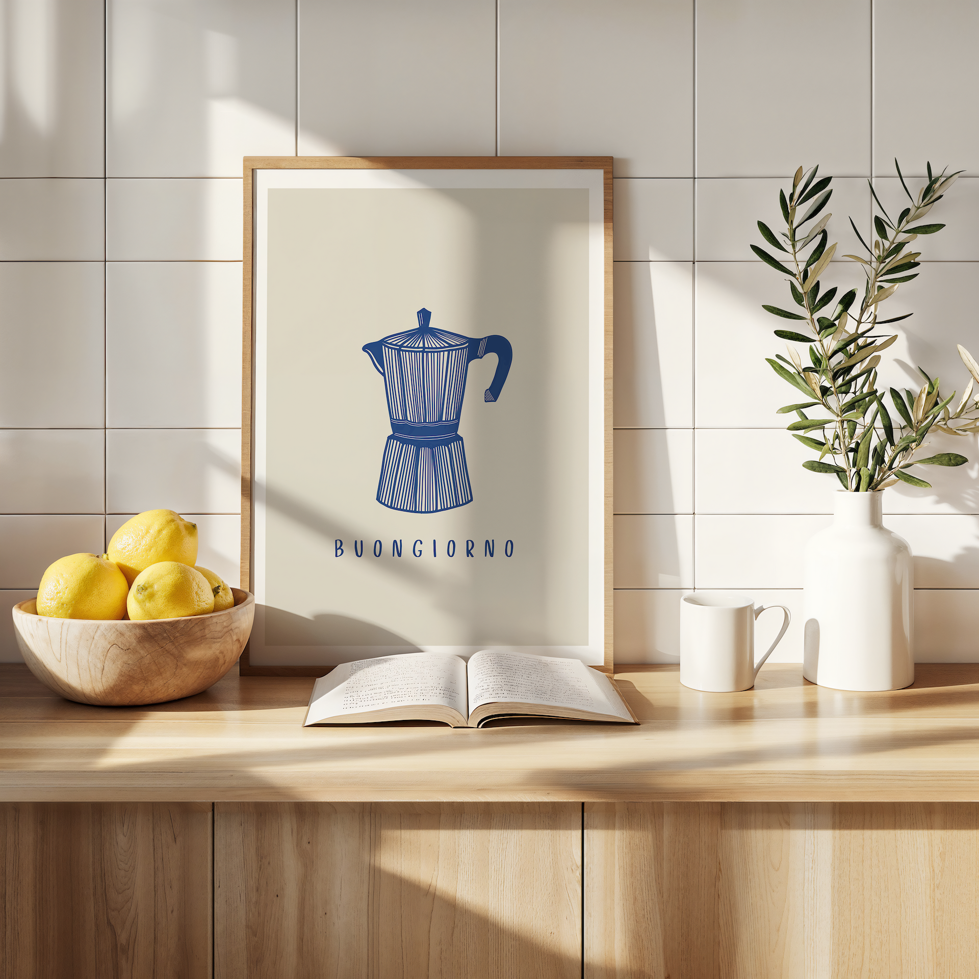 One of our popular prints featuring a navy moka coffee pot on a beige background. The print is leaning against a kitchen wall surrounded by decorative items, plants and fruit bowl.