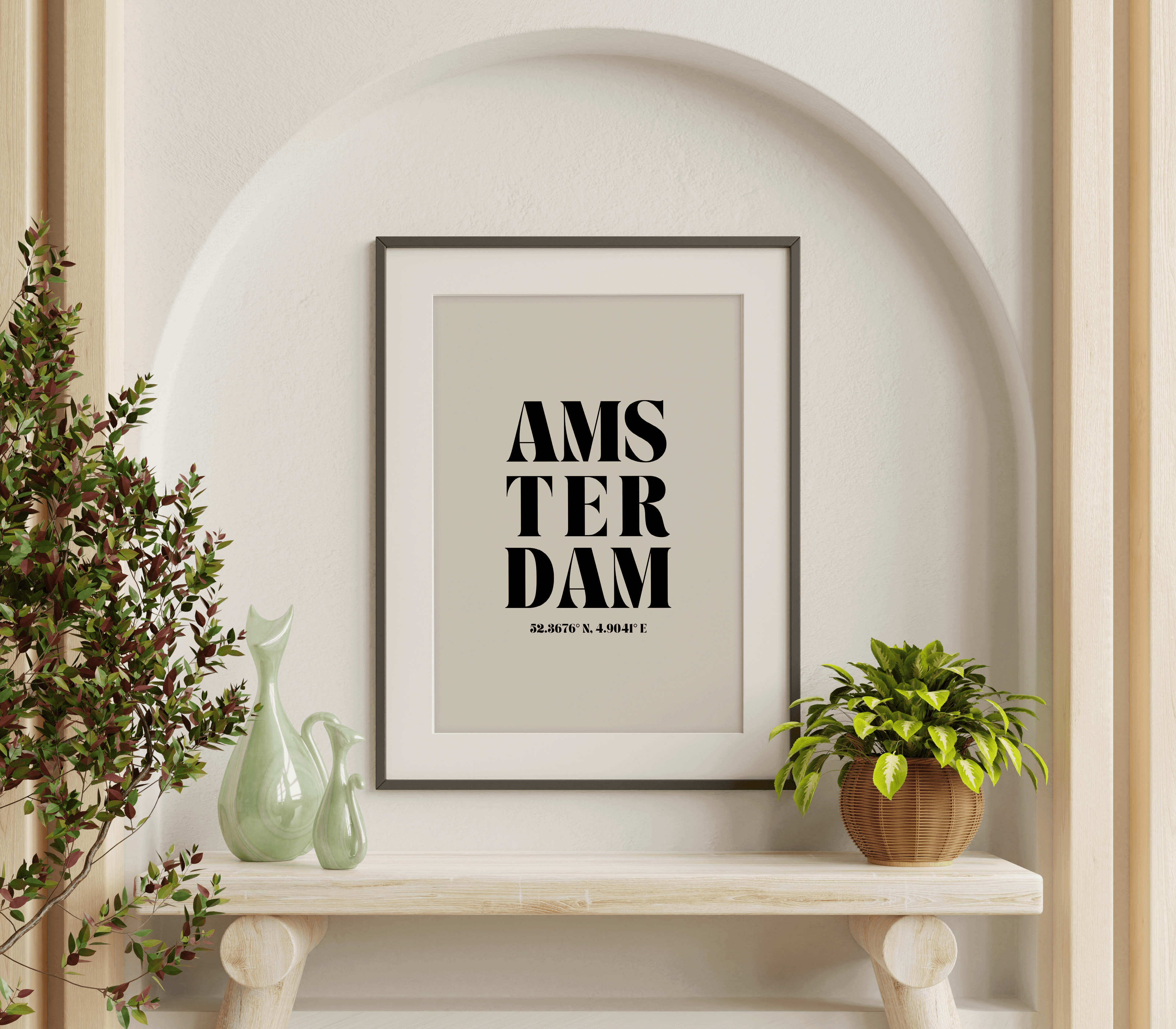"Amsterdam" typography print featuring coordinates, displayed in a wall hung frame above a bench in a room with neutral decor and decorative plants.