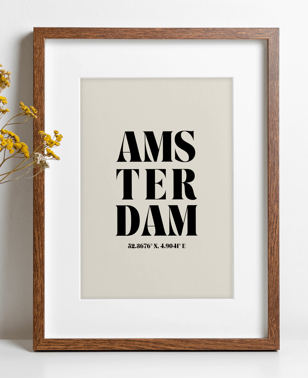 A framed poster print with the word 'Amsterdam' written in a bold, black script, centered on a neutral background.