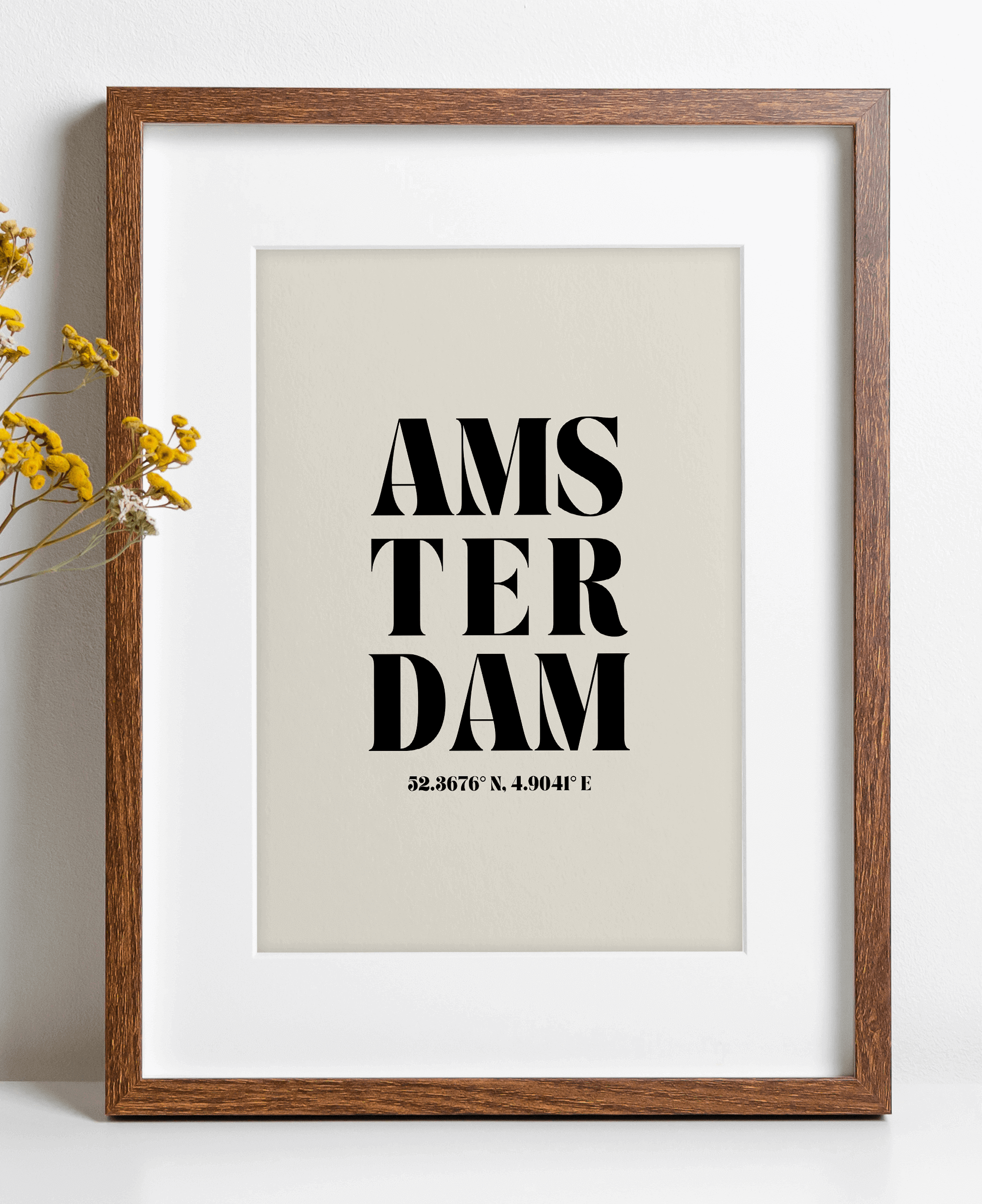 A framed poster print with the word 'Amsterdam' written in a bold, black script, centered on a neutral background.