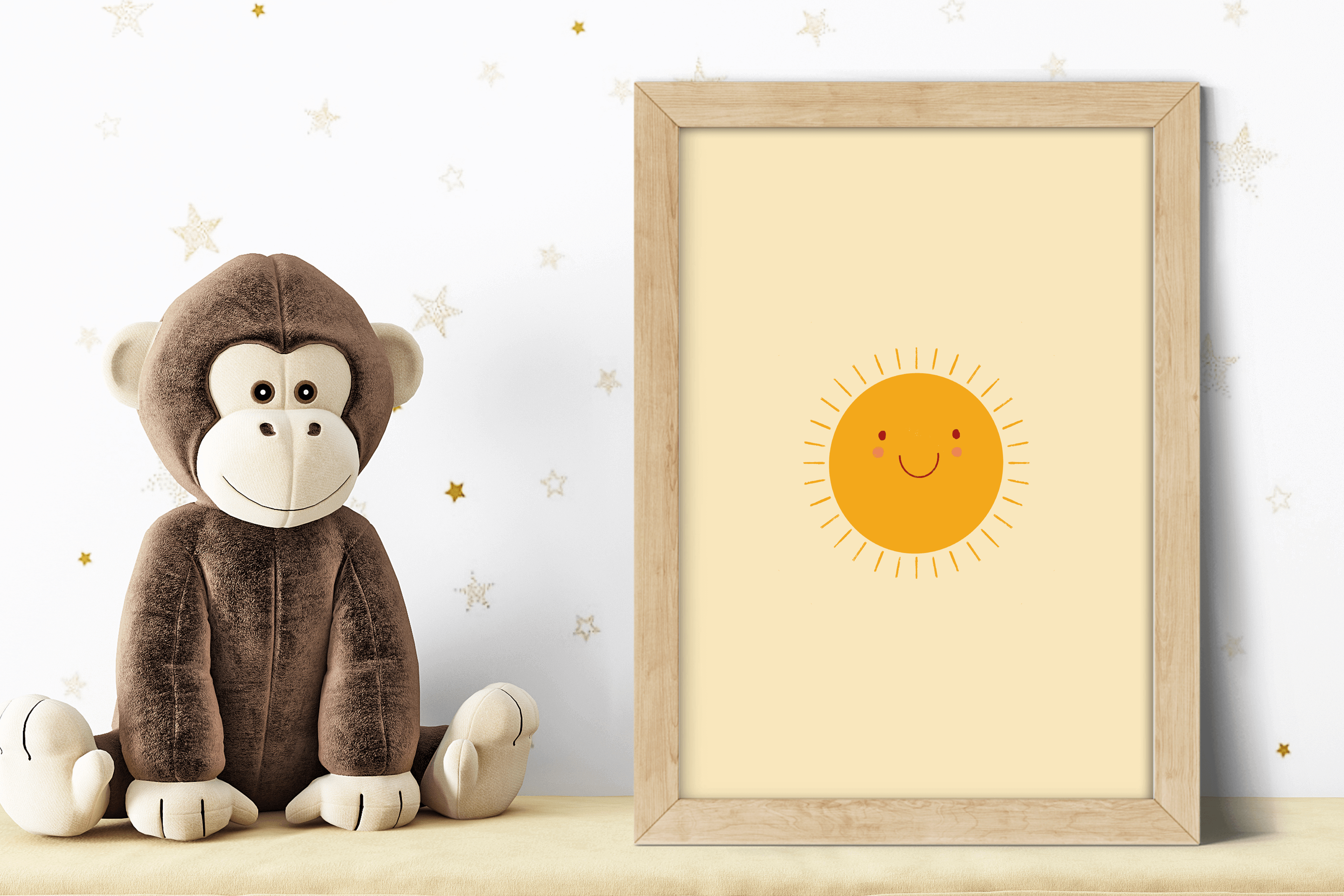 Children's poster featuring a smiling soon, displayed in a wooden frame alongside a plush toy monkey.