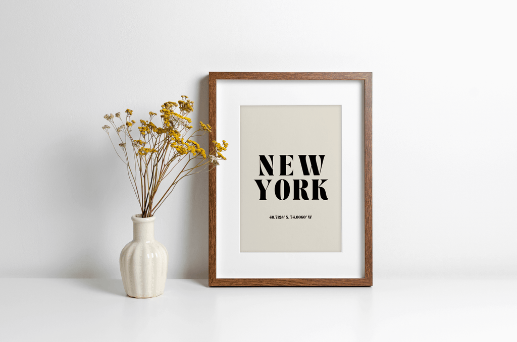 "New York" typography print featuring coordinates, displayed in a wall leaning frame in a room with neutral decor.