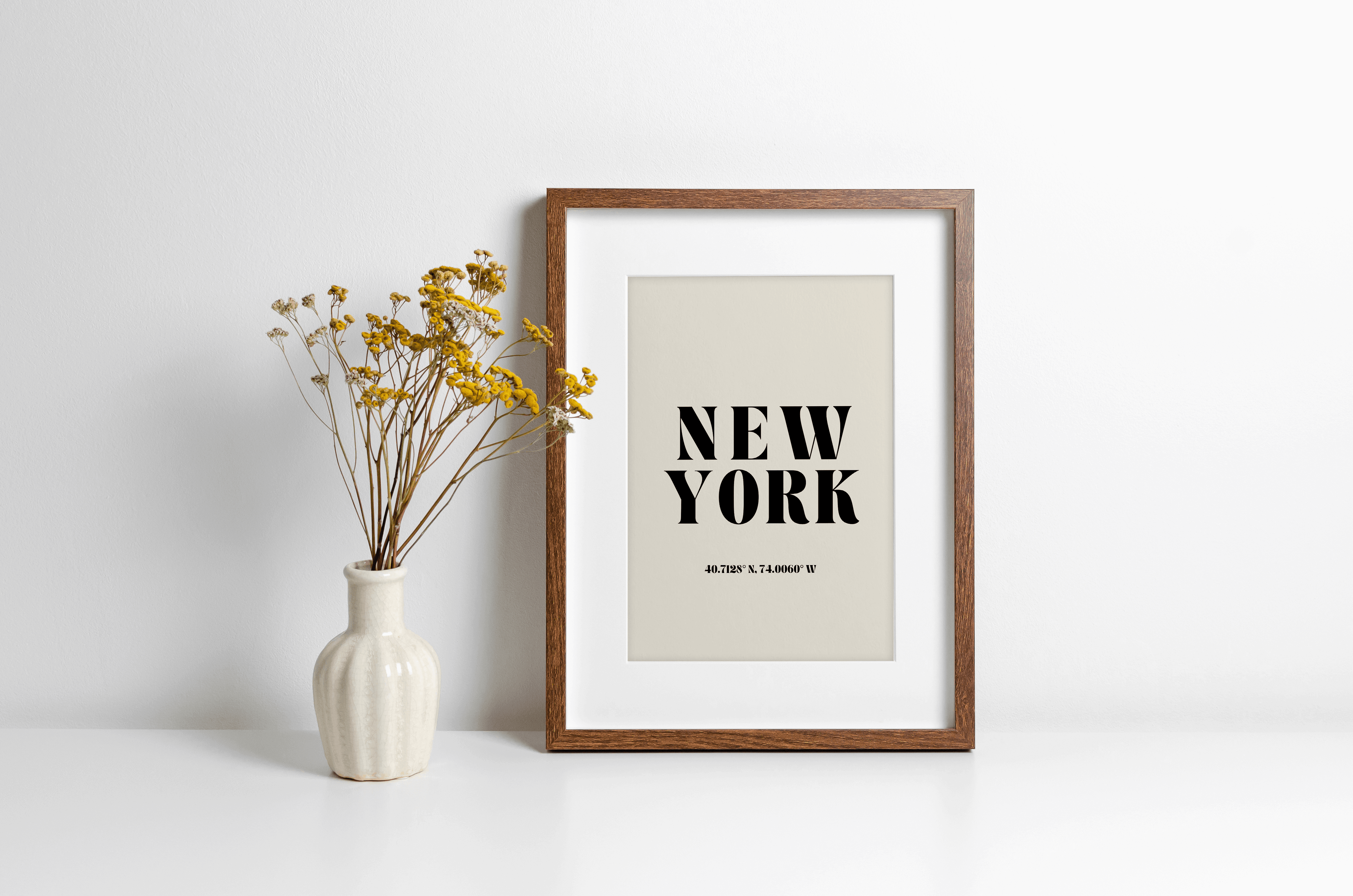"New York" typography print featuring coordinates, displayed in a wall leaning frame in a room with neutral decor.
