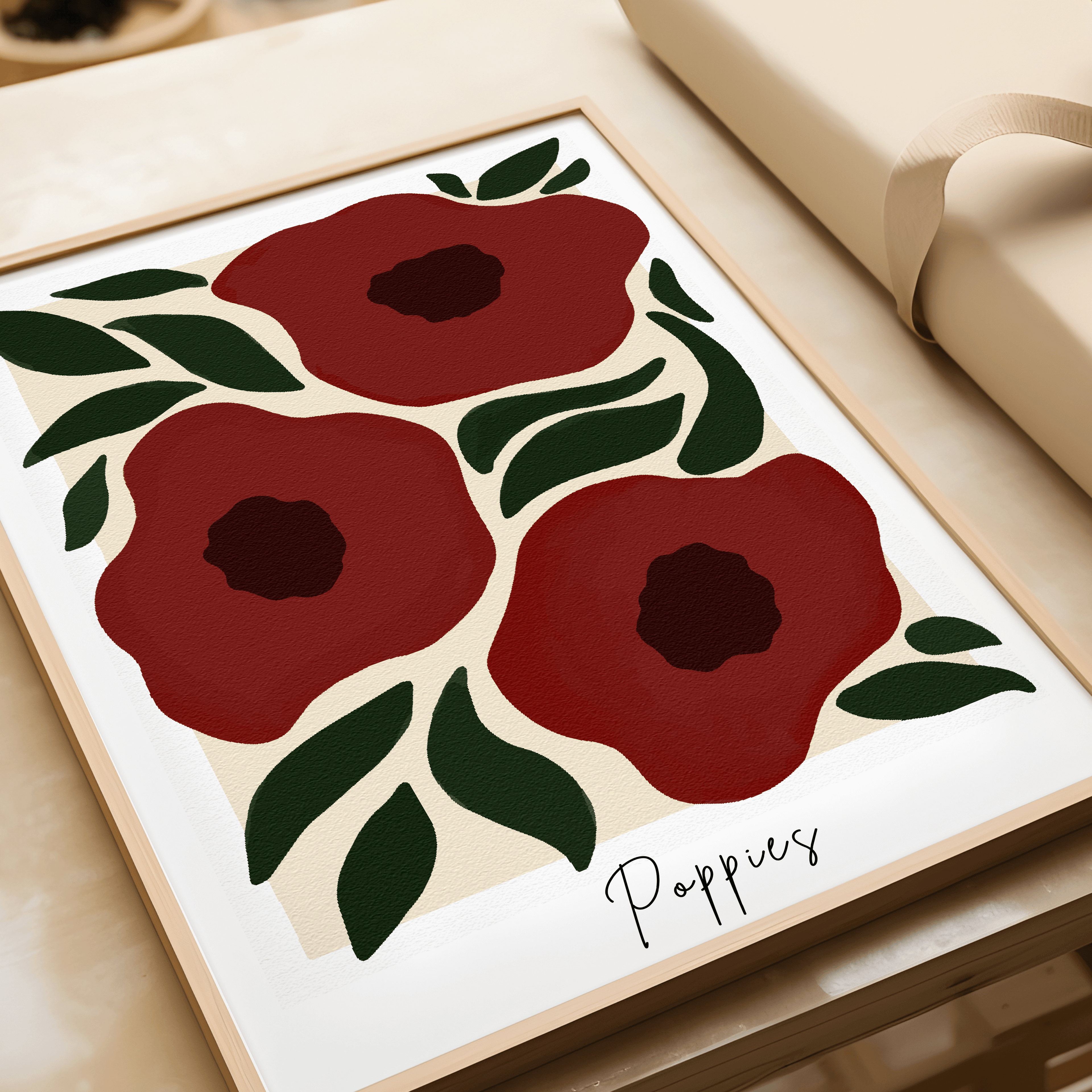 Framed artwork of red poppies with green leaves on a beige surface