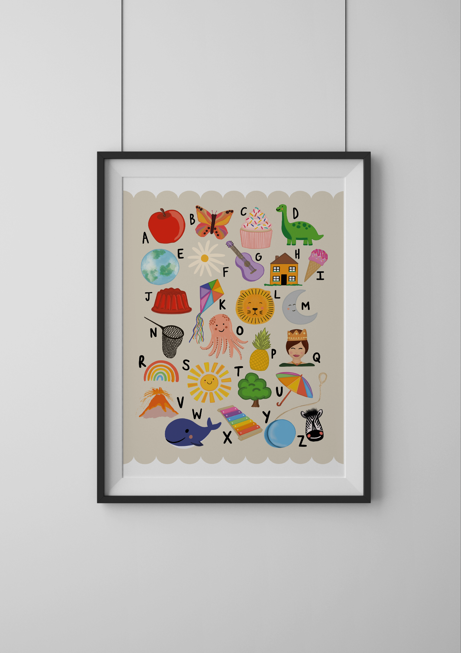 Framed alphabet poster with colorful illustrations on a white wall