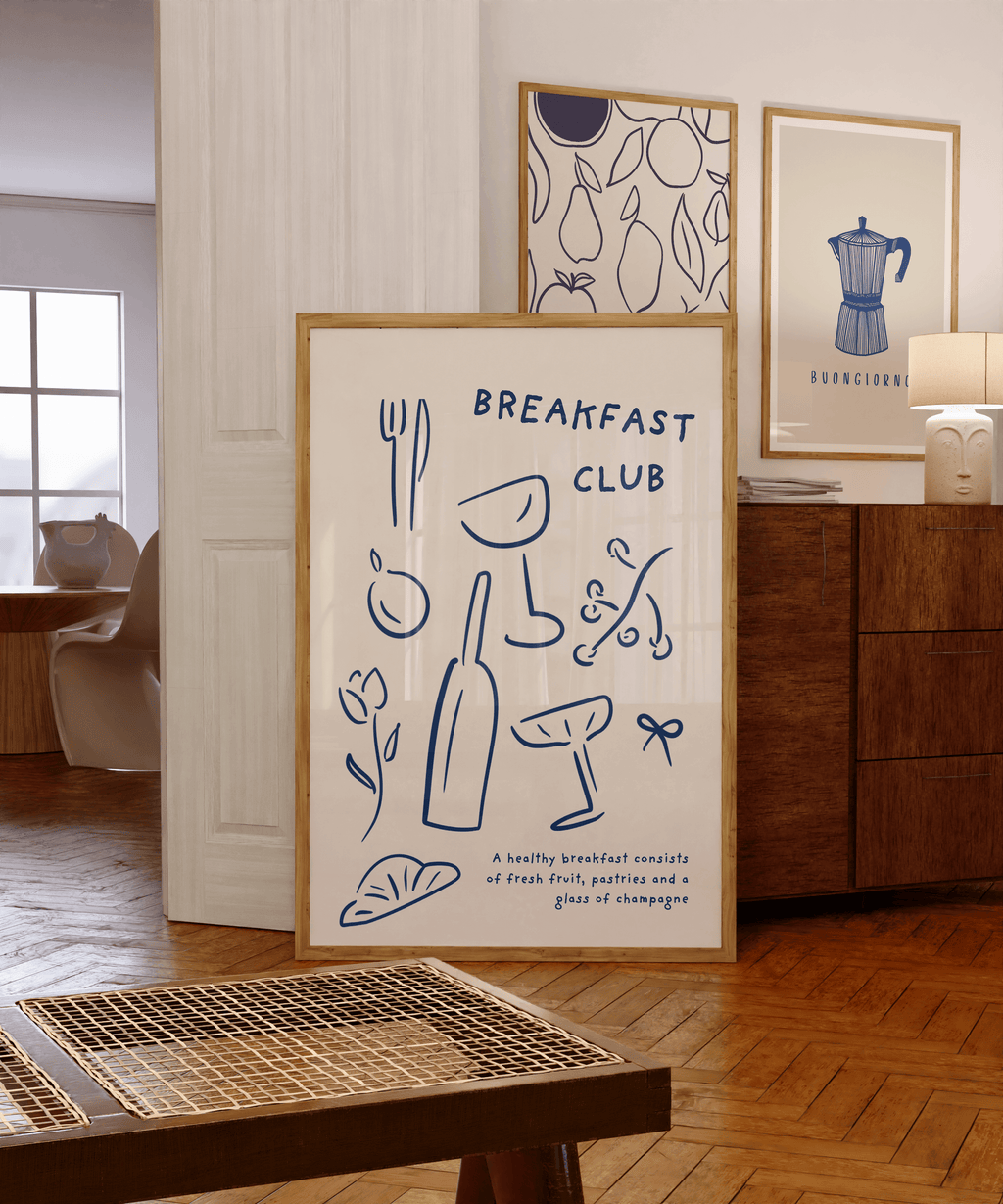 Framed artwork with 'Breakfast Club' text and illustrations in a room with wooden furniture and a lamp.