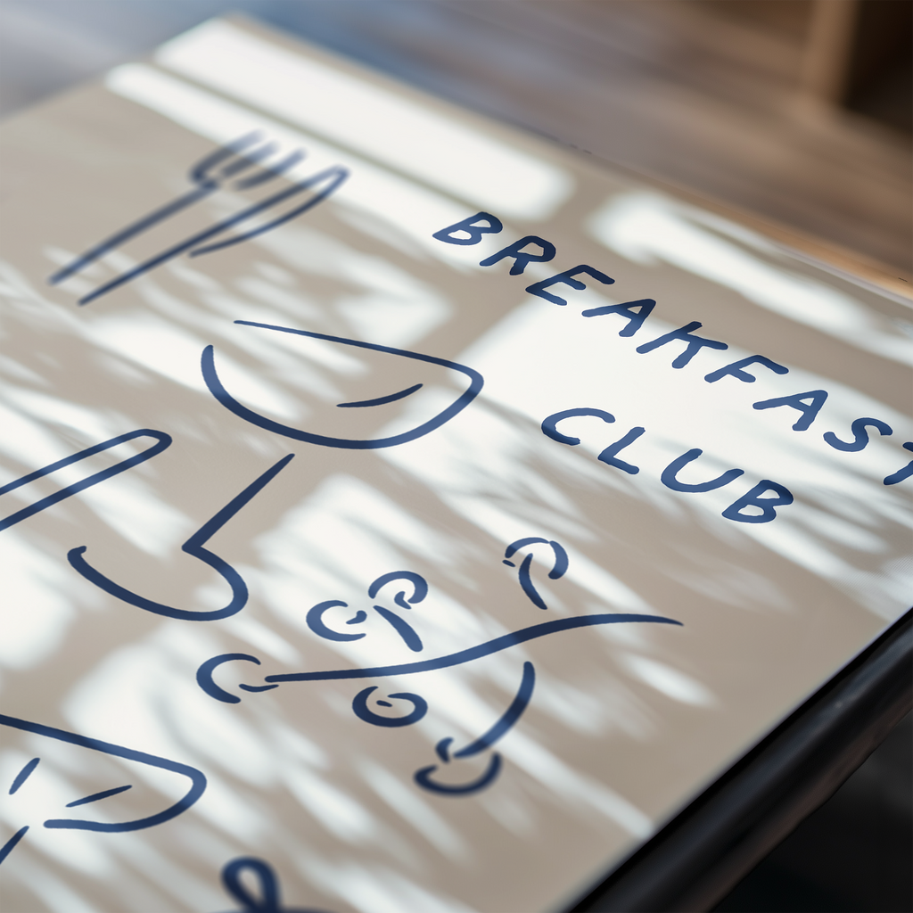 Tablet displaying 'Breakfast Club' with decorative text on a light surface.