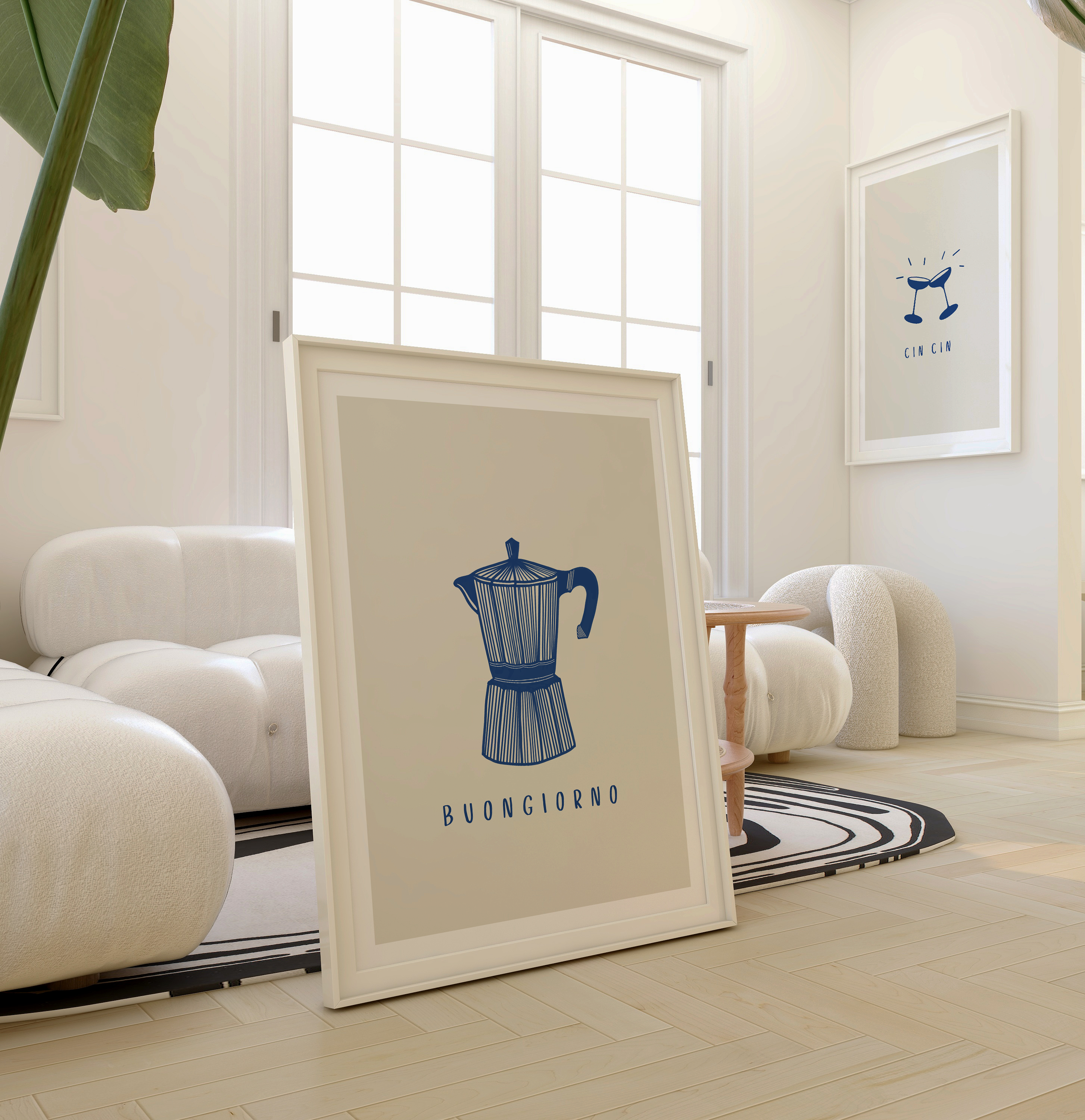 Italian coffee art print leaning against table in white room. The print features a moka pot illustration and "Buongiorno" typography, beige background and white border. "Cin Cin" wall hung print is shown in back of image.