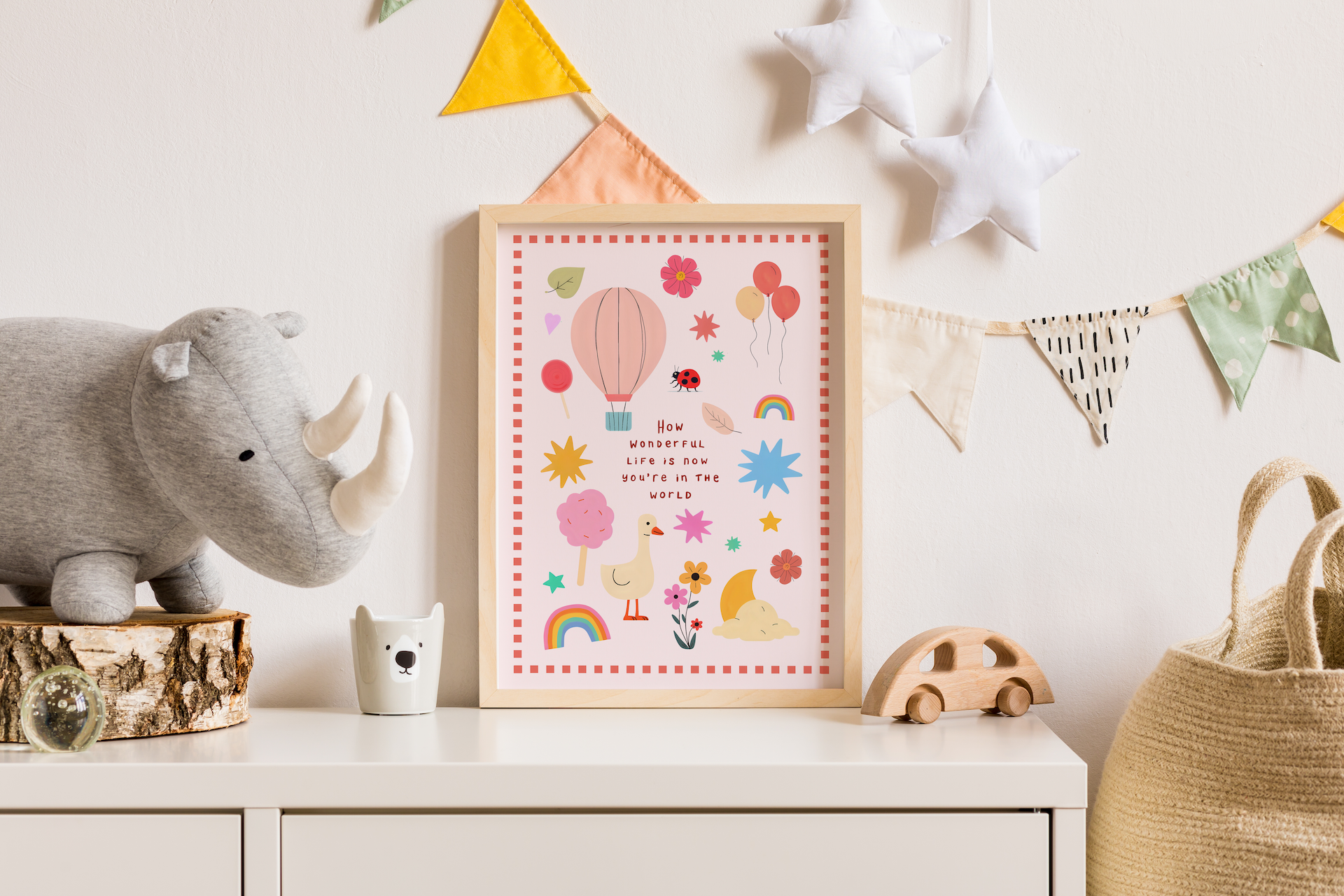 Framed children's poster with colorful illustrations on a white shelf with toys and decor.
