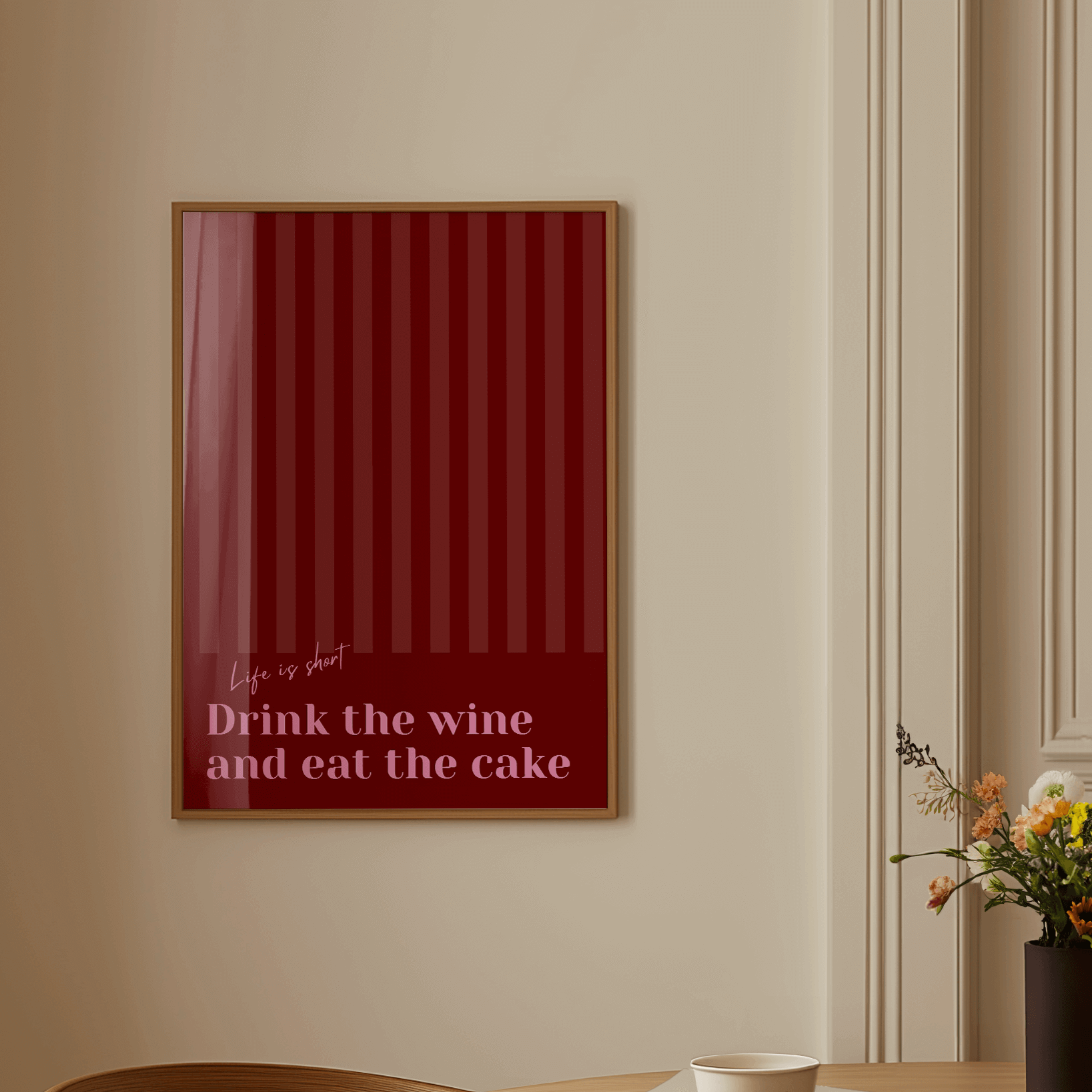 Red and pink typography print, in a wall hung frame featuring the quote "Life is short. Drink the wine and eat the cake"