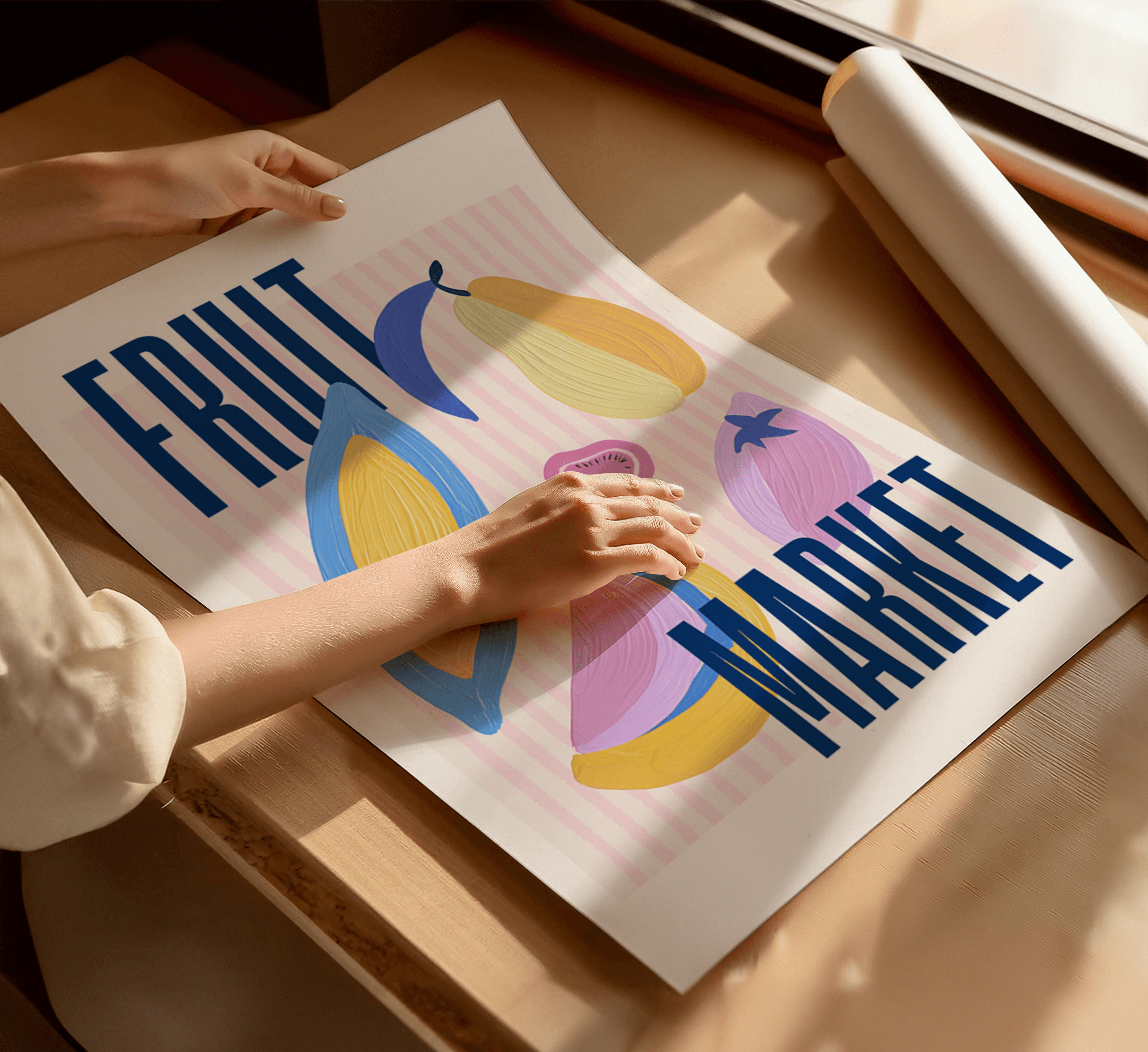 Person holding a art print with colourful fruit illustrations and text on a wooden surface.