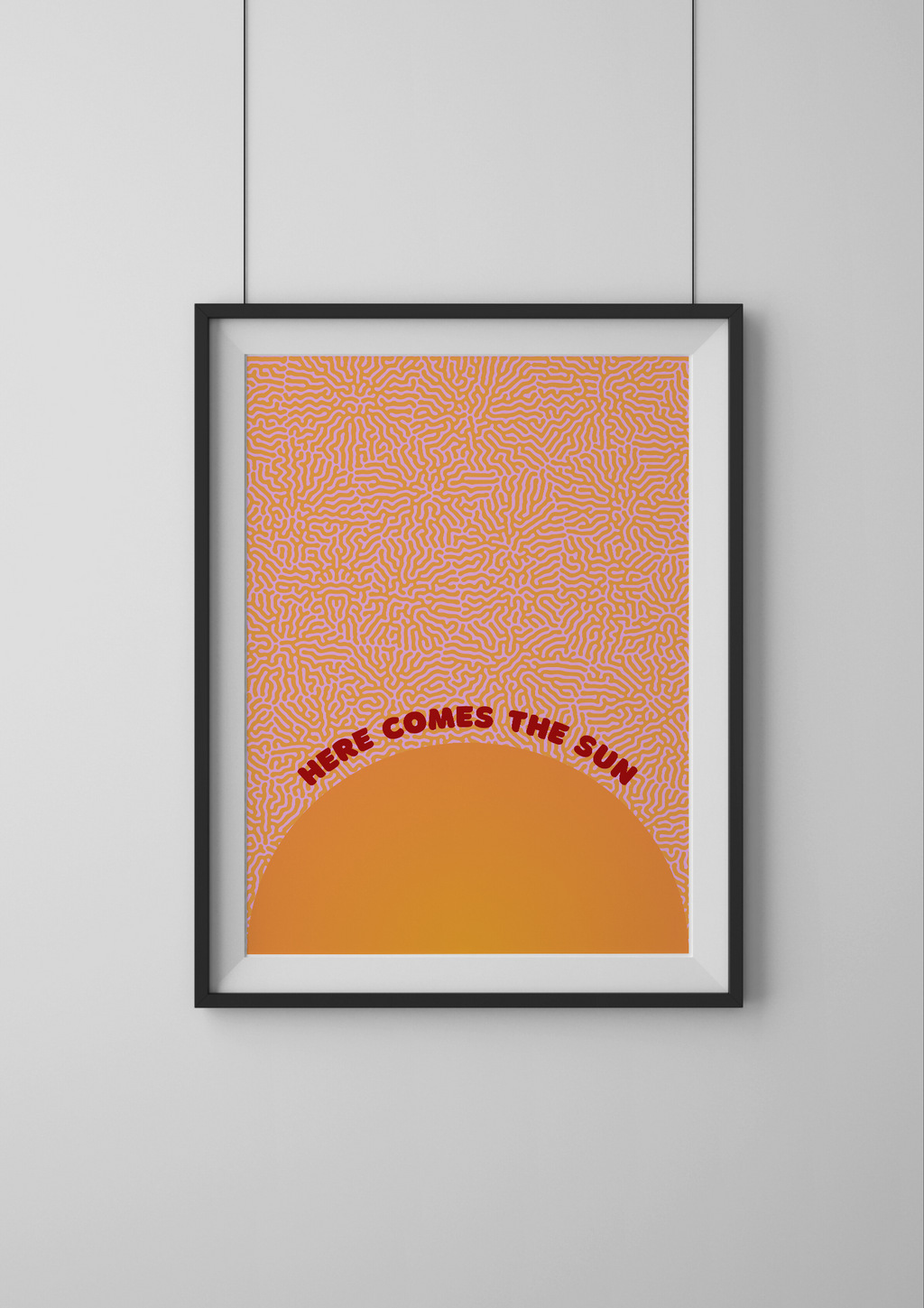 Framed artwork with a geometric pattern and text 'Here Comes the Sun' on an orange background.