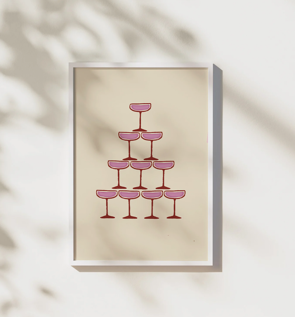 Framed pink champagne print hanging on a white wall