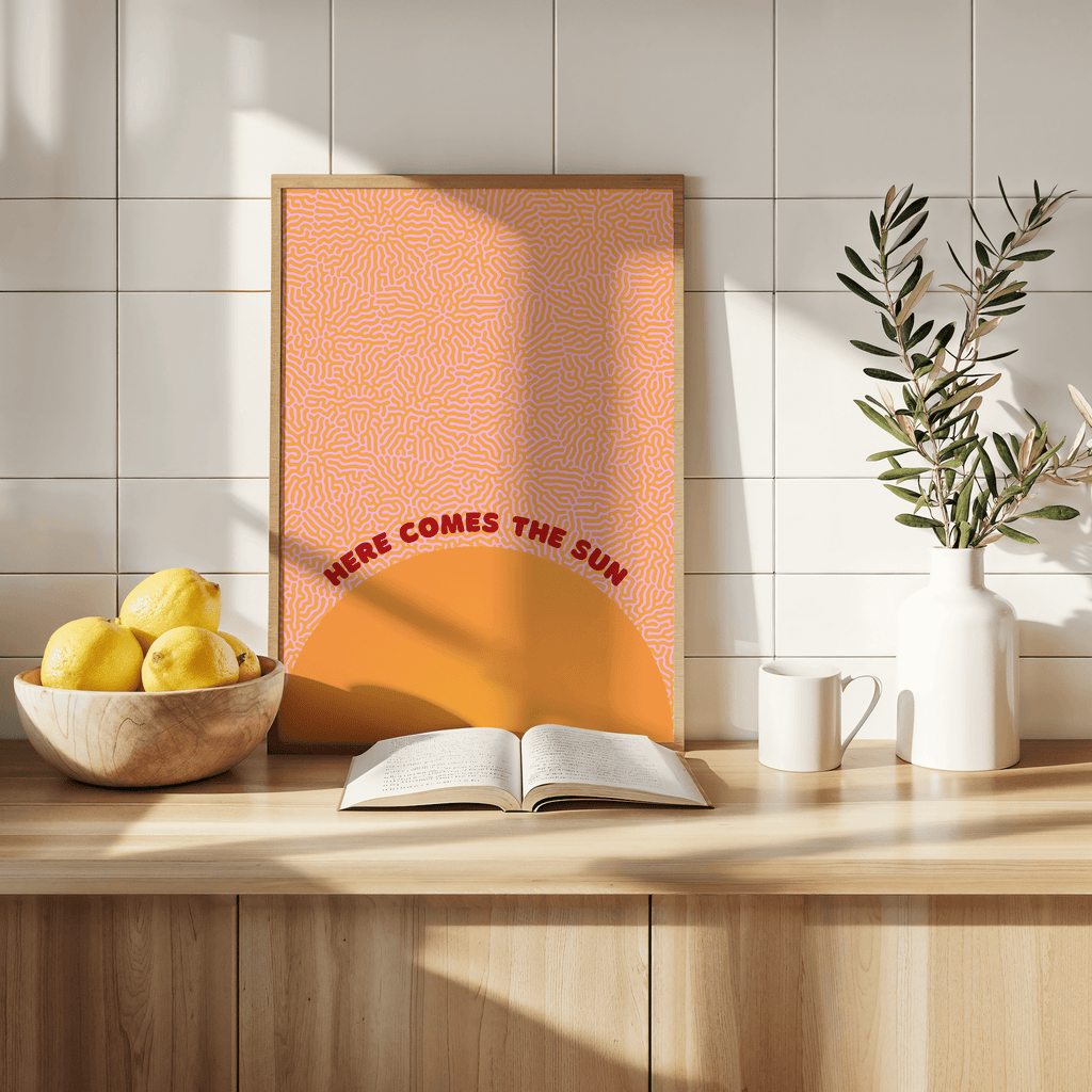 Here comes then sun music art print with vibrant colours on a kitchen countertop surrounded by decorative items and fruit.