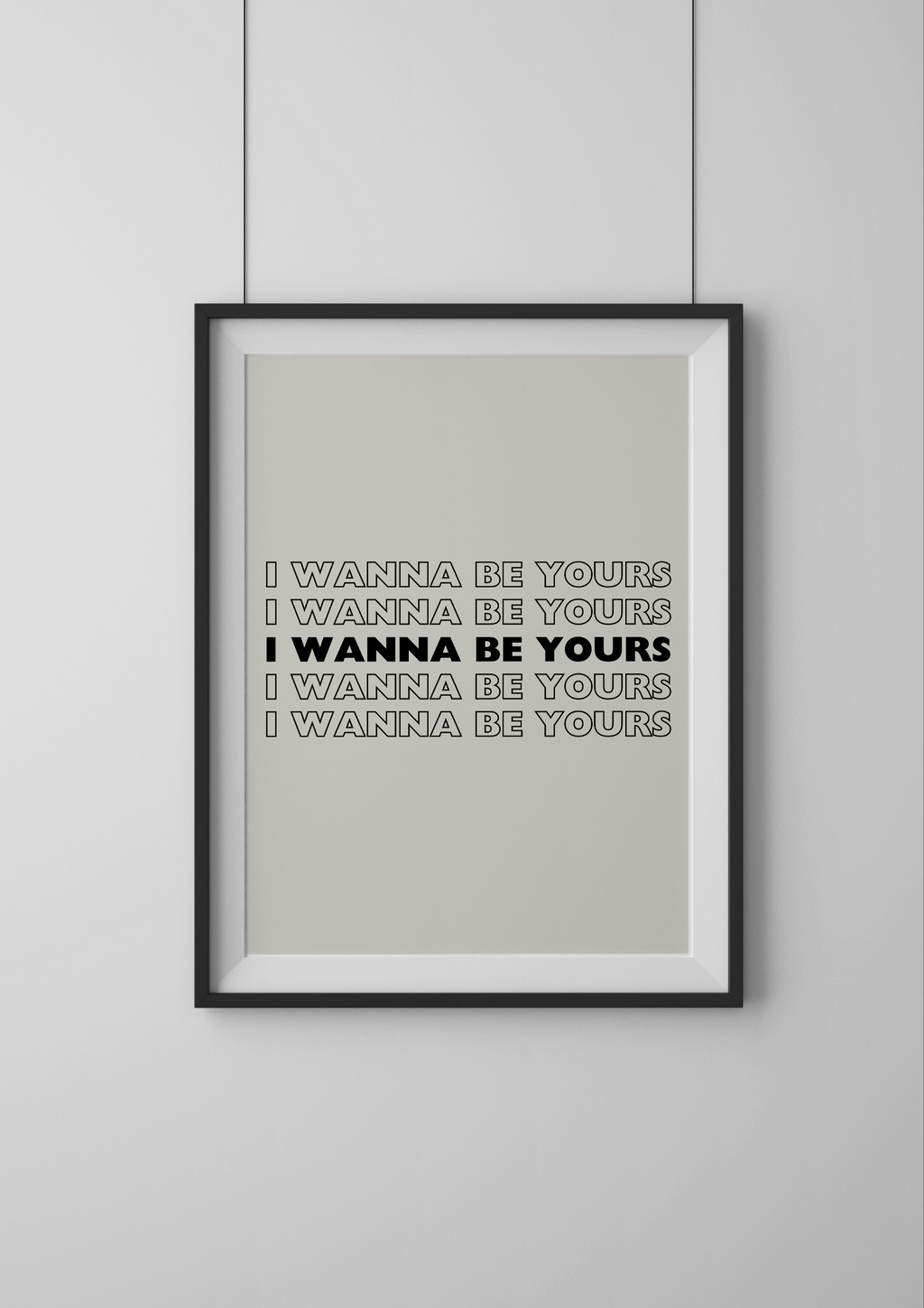 Framed artwork with text 'I WANNA BE YOURS' on a plain wall.